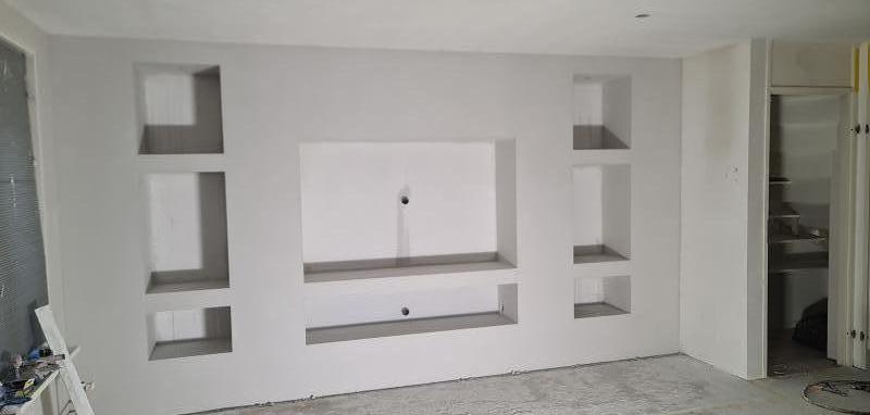 Afgewerkte wand met ingebouwde nissen en een vlak voor de televisie