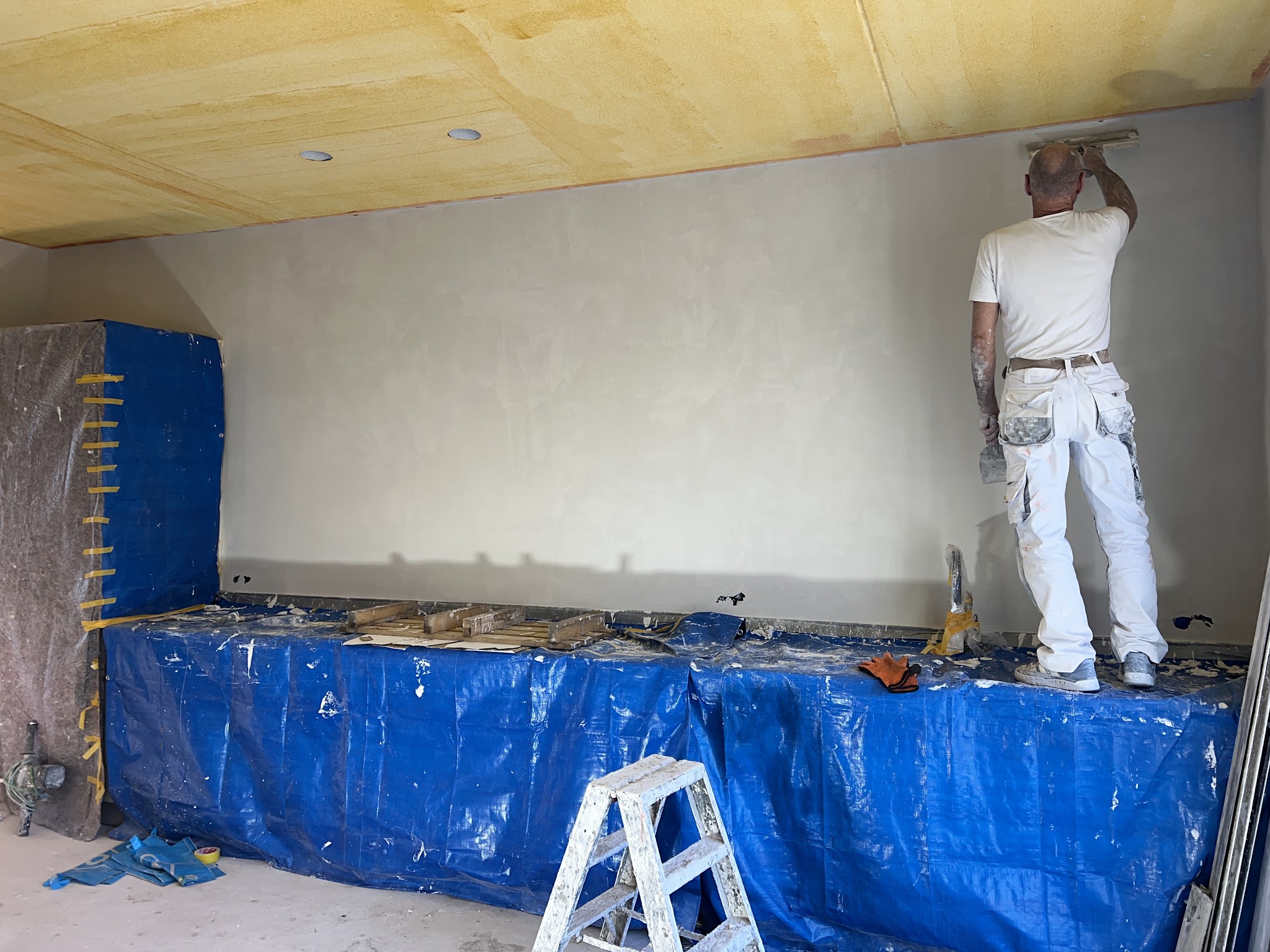 Stucwerk in uitvoering: een lange wand in een nieuwbouwwoning wordt glad gestuct