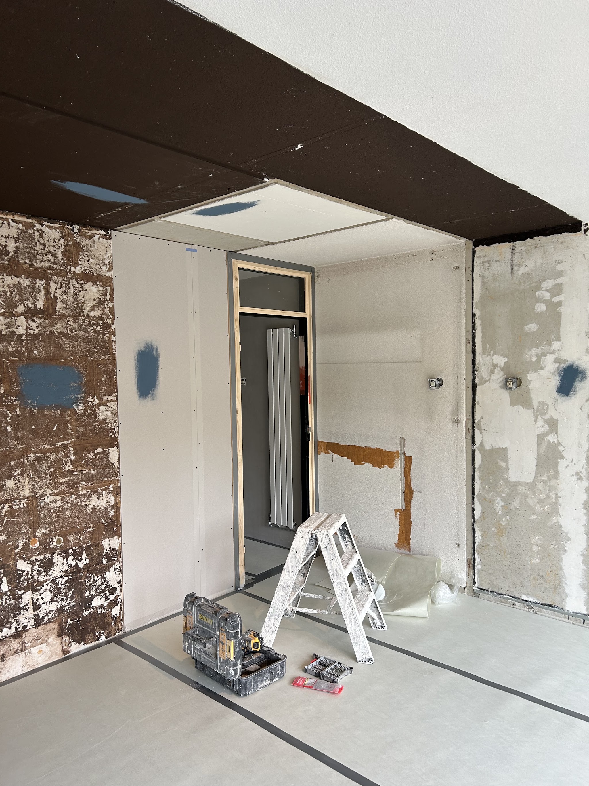 Kamer tijdens de verbouwing: oude wanden, nieuwe gipsplaten en gereedschap op de vloer
